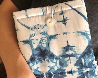 Könnte beinhalten: Eine Stoffhülle mit weißem und blauem Muster und Knopfverschluss. Der Stoff hat ein Design im Batik-Stil in Blautönen. Die Hülle ist für ein Tablet oder einen E-Reader konzipiert.