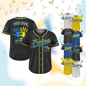 Op de afbeelding: Een zwart baseballshirt met gele en blauwe bies. De voorkant van het shirt heeft de tekst "Frontext" in blauw en een hart met een handafdruk in blauw en geel. De achterkant van het shirt heeft de tekst "Your Name" en een handafdruk met de tekst "Down Syndrome Aware". Het shirt wordt getoond in acht verschillende kleurvariaties.