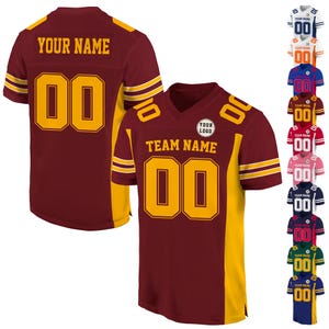 May include: A maroon and gold football jersey with a white collar and gold stripes on the sleeves. The jersey has a large number "00" on the front and back, and the text "YOUR NAME" is printed on the back. The jersey is customizable with your own team name and logo.