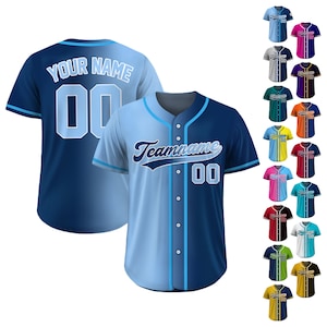 May include: A blue and light blue baseball jersey with a white number 00 and the text "Your Name" on the front. The back of the jersey has the text "Teamname" and the number 00 in a white font. The jersey has a button-up front and short sleeves.