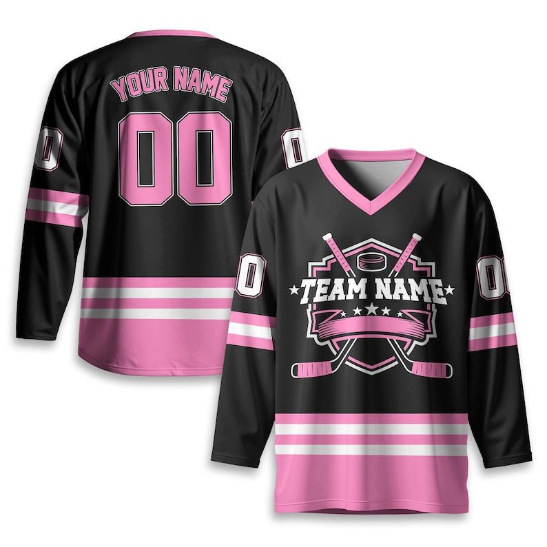 May include: Black hockey jersey with pink accents, featuring a V-neck and long sleeves. The jersey displays the text "TEAM NAME" and "YOUR NAME" with the number "00". Pink and white stripes adorn the sleeves and bottom hem.