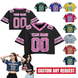 May include: Black and pink glitter-detailed crop top football jerseys with the text "YOUR NAME" and "TEAM NAME" and the number "00". A variety of colored jerseys are also shown. The image includes the text "CUSTOM ANY REQUEST".