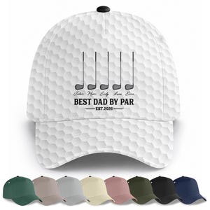 以下が含まれることがあります： ハニカム模様の白いゴルフキャップ。ゴルフのクラブと「BEST DAD BY PAR EST.2026」の文字が特徴です。キャップの上部には黒いボタンがあり、さまざまな色の野球帽と一緒に表示されています。