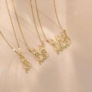 May include: Five gold necklaces with cat-shaped pendants. Each pendant has a different name inscribed on it: Bella, Sienna, Leo, Lucy, and Coco.