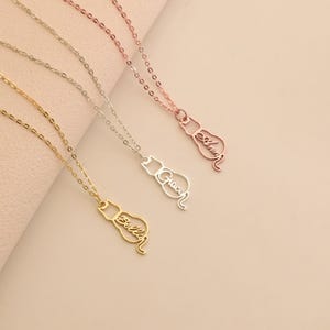 May include: Three gold, silver, and rose gold necklaces with cat-shaped pendants. Each pendant has a name inscribed in cursive: "Gracen", "Allison", and "Anya".