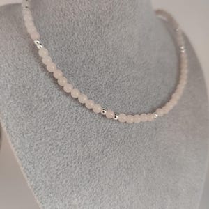 Könnte beinhalten: Eine zarte Halskette aus rosa und silbernen Perlen. Die Halskette besteht aus kleinen, runden Perlen mit einem dezenten Schimmer. Die Perlen sind auf einer silbernen Kette aufgefädelt.