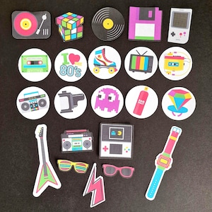 May include: A set of 18 colourful 80s themed party favour stickers. The stickers feature retro icons like a cassette tape, a boombox, a Rubik's cube, a video game, a ghost, a hairspray can, a diamond ring, a wristwatch, a guitar, a pair of sunglasses, a lightning bolt, and a boombox. The stickers are perfect for adding a touch of 80s nostalgia to your party decorations.