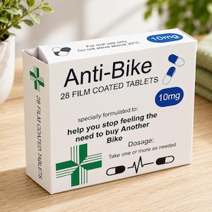 May include: A white rectangular box labeled Anti-Bike 28 film coated tablets 10mg. The packaging features blue and white capsule illustrations, a green cross symbol, and text stating: specially formulated to help you stop feeling the need to buy Another Bike.