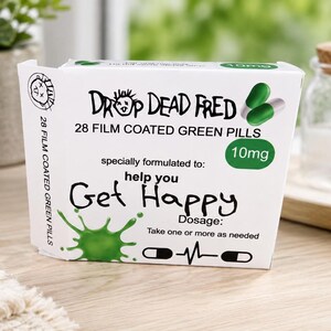 May include: A white rectangular box labeled Drop Dead Fred containing 28 film coated green pills at 10mg. The front features a green splash graphic, the text help you Get Happy, and dosage instructions to take one or more as needed with a pulse icon.