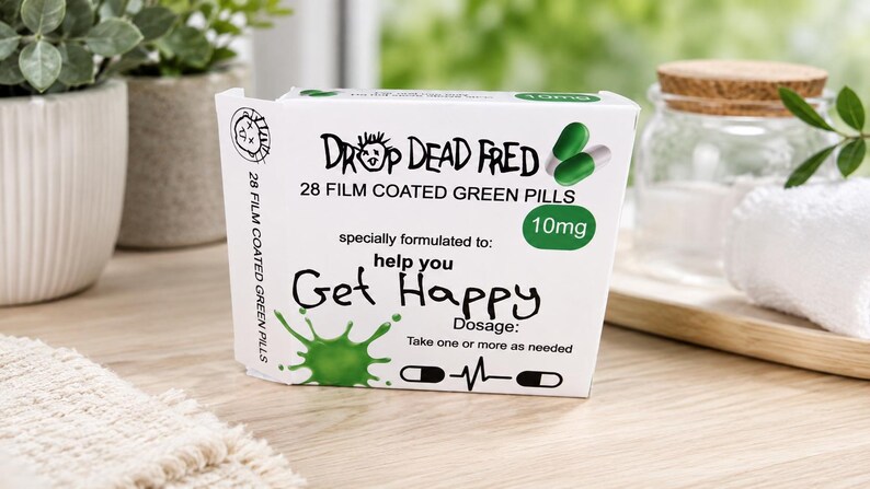 May include: A white rectangular box labeled Drop Dead Fred containing 28 film coated green pills at 10mg. The front features a green splash graphic, the text help you Get Happy, and dosage instructions to take one or more as needed with a pulse icon.