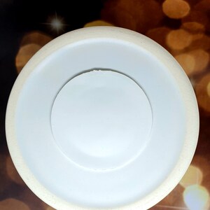 Może przedstawiać: Biały talerz ceramiczny z mniejszym białym talerzem ceramicznym w środku. Talerz jest okrągły i ma gładką powierzchnię.