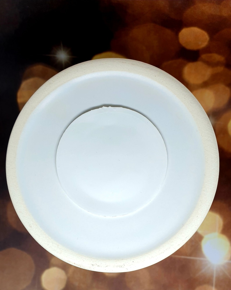 Może przedstawiać: Biały talerz ceramiczny z mniejszym białym talerzem ceramicznym w środku. Talerz jest okrągły i ma gładką powierzchnię.