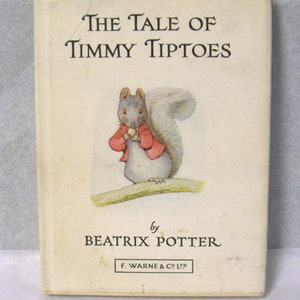 Op de afbeelding: De omslag van het boek "The Tale of Timmy Tiptoes" met een grijze eekhoorn die een rood jasje draagt en een noot vasthoudt. Het boek is van Beatrix Potter en uitgegeven door F. Warne & Co. Ltd.