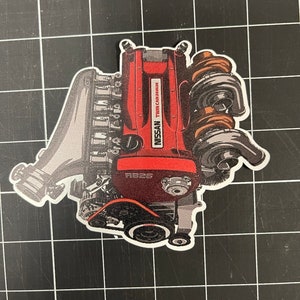 May include: A red and gray illustration of a Nissan Twin Cam engine with the text "RB25" and "NISSAN TWIN CAM 24 VALVE" on it.