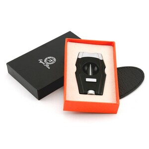 May include: A black and silver cigar cutter in a red and white box. The cutter has a guillotine style blade and a  "Cigar Star" logo on the box.