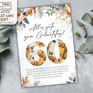Op de afbeelding: Een witte kaart met een bloemenontwerp en de tekst "Alles gute zum Geburtstag!" met een 60 gemaakt van 50 eurobiljetten.