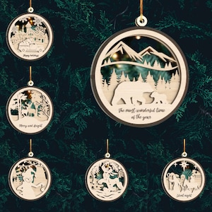 May include: Set of six wooden Christmas ornaments with intricate laser cut designs. Each ornament features a different winter scene, including a snowy village, a forest with deer, a mountain range with bears, a snowman, a reindeer pulling a sleigh, and a nativity scene. The ornaments are decorated with the phrases "Happy Holidays", "Merry and Bright", "The most wonderful time of the year", "Silent Night", and other festive sayings.
