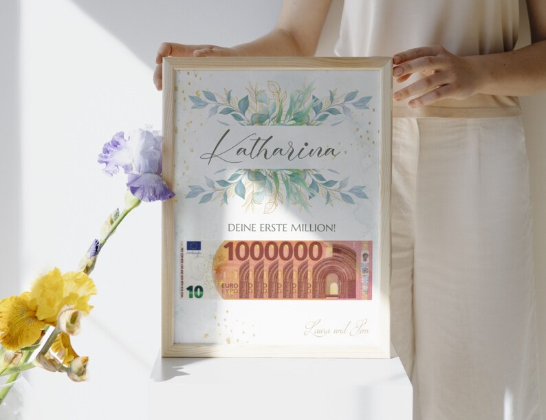 May include: A framed print with a watercolor floral design and gold glitter. The print says "Katharina" and "Deine erste Million!" with a 100,000 Euro bill image. The print is signed "Laura und Jan."