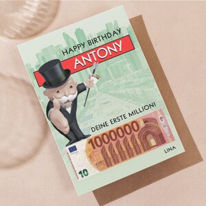 May include: A green and white birthday card featuring a cartoon Monopoly Man character with a top hat and a monocle. The card has the text "Happy Birthday Antony" and "Deine erste Million!" with a large euro bill in the bottom right corner. The card is signed "Lina".