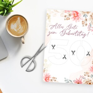 May include: A white card with a floral design and the text "Alles Gute zum Geburtstag!" with the number 50 in a cut-out design. Scissors are shown in the cut-out areas of the number 50.