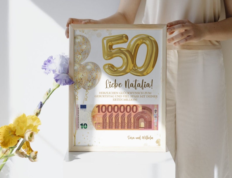 K&ouml;nnte beinhalten: Eine gerahmte Geburtstagskarte mit einer goldenen Ballonnummer 50, Konfetti und einem Euro-Banknoten mit dem Text "Liebe Natalia! Herzlichen Gl&uuml;ckwunsch zum Geburtstag und viel Spass mit deiner ersten Million! 1000000 Sara und Wilhelm"