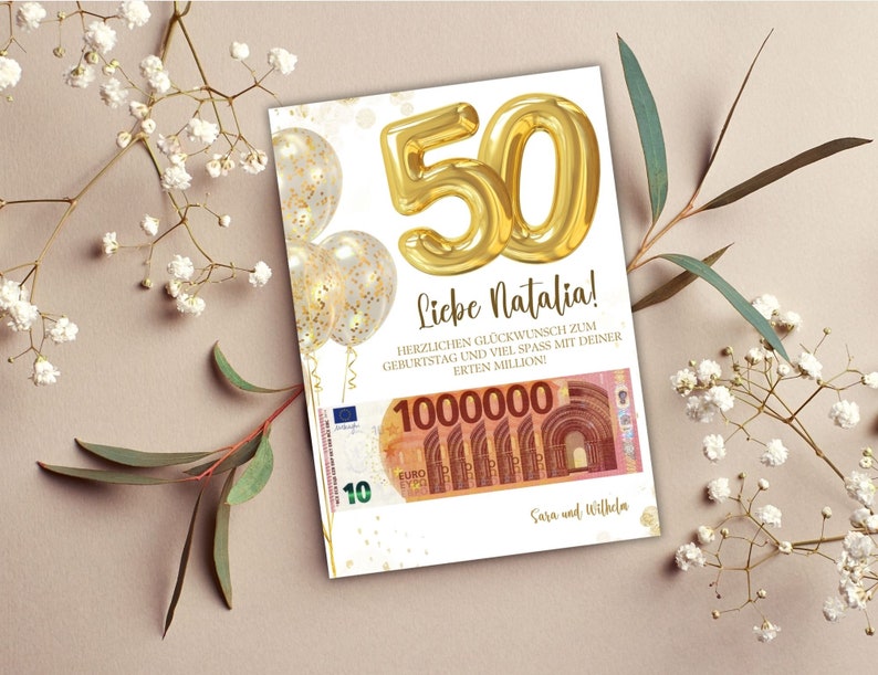 K&ouml;nnte beinhalten: Eine wei&szlig;e Karte mit goldenem Konfetti und einem goldenen Ballon in Form der Zahl 50. Die Karte tr&auml;gt den Text "Liebe Natalia!" und "HERZLICHEN GL&Uuml;CKWUNSCH ZUM GEBURTSTAG UND VIEL SPASS MIT DEINER ERTEN MILLION!"  Die Karte zeigt au&szlig;erdem ein Bild eines 10-Euro-Scheins mit der Nummer 1000000 darauf. Die Karte ist signiert mit "Sara und Wilhelm."