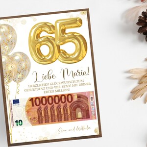 Op de afbeelding: Een ingelijste verjaardagskaart met een gouden "65" ballonontwerp. De kaart bevat Duitse tekst, gouden confetti ballonnen en een afbeelding van een miljoen euro biljet. Het is een verjaardagscadeau.