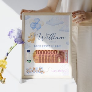 Op de afbeelding: Een ingelijst afdruk met een blauwe en witte aquarel achtergrond. De afdruk toont een teddybeer die ballonnen vasthoudt, een biljet van 10 euro en de tekst "William, Deine Erste Million!" De afdruk is in een houten lijst.