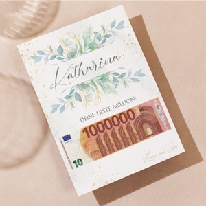 May include: A white card with gold glitter and green watercolor leaves. The card says "Katharina, Deine erste Million!" with a 100,000 euro bill underneath. The card is signed "Laura und Tom."