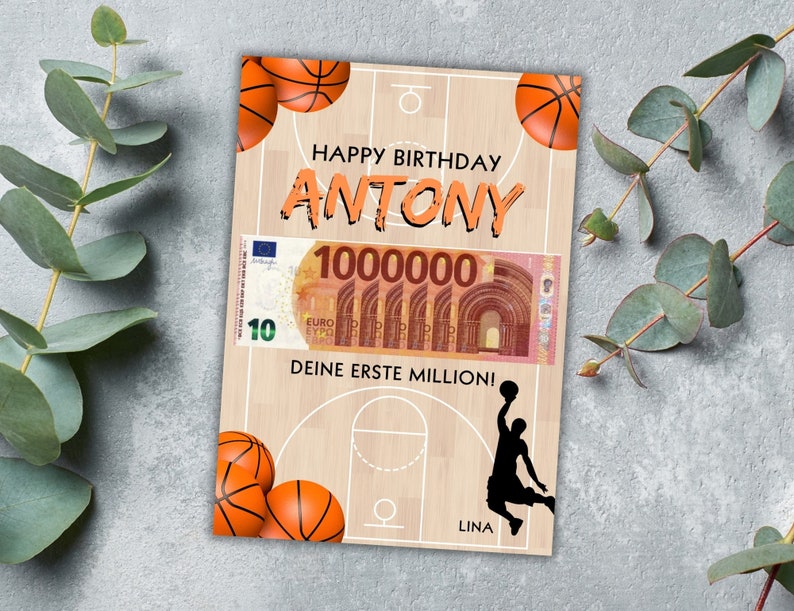 Puede incluir: Una tarjeta de cumplea&ntilde;os con tem&aacute;tica de baloncesto con un dise&ntilde;o de cancha de baloncesto, dos balones de baloncesto y una silueta de un jugador de baloncesto. La tarjeta dice "Happy Birthday Antony" y "Deine erste Million!" que se traduce como "&iexcl;Tu primer mill&oacute;n!"