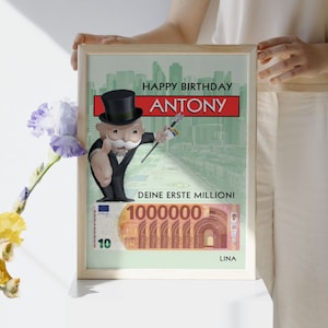 May include: A framed birthday card featuring a cartoon Monopoly Man character with a green background and the text "Happy Birthday Antony. Deine erste Million!" and a 10,000 Euro bill.