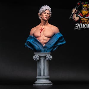 Könnte beinhalten: Eine Büste eines Menschen mit weißen Haaren und einem blauen Gewand. Die Person hat Blut auf der Brust und schaut zur Seite. Die Büste steht auf einem grauen Sockel.