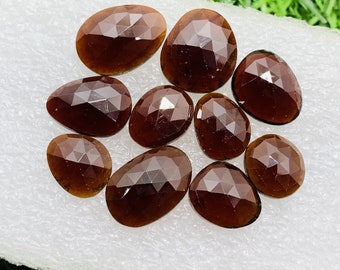 Pode incluir: Uma coleção de dez pedras preciosas marrons facetadas, cada uma com um formato e tamanho únicos. As pedras têm uma cor castanho rica e profunda e um acabamento liso e polido.