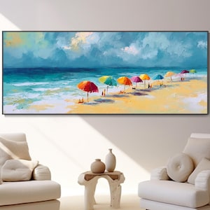 May include: A long, rectangular canvas print shows a beach scene with colourful umbrellas. The artwork features a vibrant blue ocean, a sandy shore, and a cloudy sky. The umbrellas are in various colours, adding a cheerful touch to the coastal landscape.