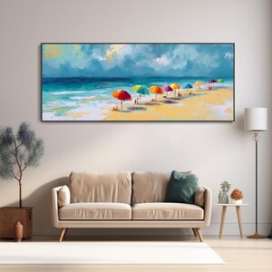 May include: A framed painting of a beach scene, featuring colourful parasols on a sandy shore. The artwork shows a bright blue sea under a cloudy sky. The painting hangs above a beige sofa.