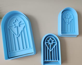 Könnte beinhalten: Drei blaue Plastik-Ausstecher in Form von Bogenfenstern mit einem Stern in der Mitte. Der größte Ausstecher ist etwa 18 cm hoch, der mittlere etwa 13 cm und der kleinste etwa 8 cm.