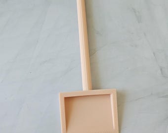 Puede incluir: Un portaseñales de plástico rosa claro con un letrero cuadrado y un palo puntiagudo.