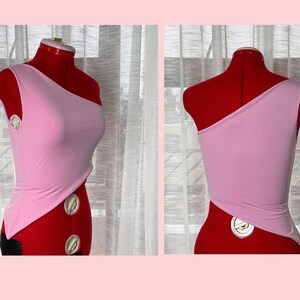 May include: A pink one-shoulder top with a diagonal cut on the front and back. The top is made of a soft, stretchy fabric.