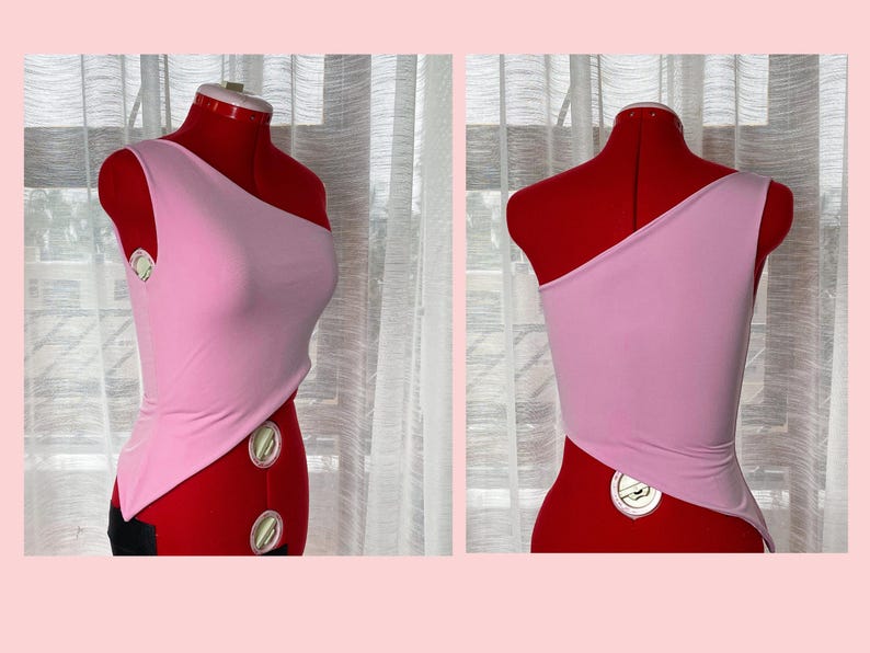 May include: A pink one-shoulder top with a diagonal cut on the front and back. The top is made of a soft, stretchy fabric.