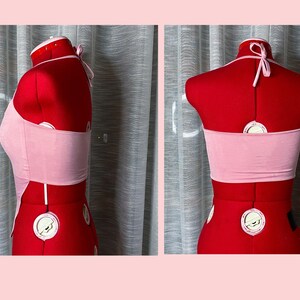 May include: Pink halter top with a thin strap design. The top is made of a soft, stretchy fabric and has a cropped fit.