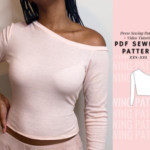 May include: A PDF sewing pattern for a long-sleeved, one-shoulder top. The pattern includes sizes XXS-XXL. The image shows a model wearing a pink version of the top.