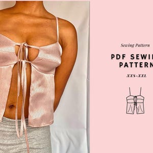 Könnte beinhalten: Ein hellrosa Satin-Top mit Spaghettiträgern und einem Bindeverschluss. Das Top hat ein Schlüssellochdetail und einen geteilten Vordereingriff. Der Text "Sewing Pattern PDF Sewing Pattern XXS-XXL" ist ebenfalls enthalten.
