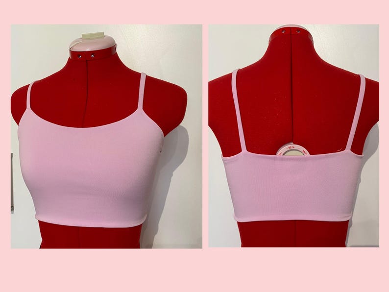 May include: A pink, sleeveless crop top with a scoop neck. The top is on a red dress form.