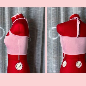 May include: A pink halter top with a thin strap. The top is made of a soft, stretchy fabric and has a cropped fit.