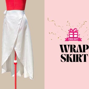 May include: A white wrap skirt with a tie closure. The skirt is on a mannequin and the background is pink with gold confetti and the text "FREE GIFT" and "WRAP SKIRT".
