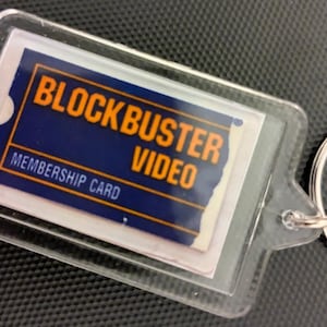 May include: A clear plastic keyring with a blue and orange Blockbuster Video membership card inside. The card says "Blockbuster Video" and "Membership Card".