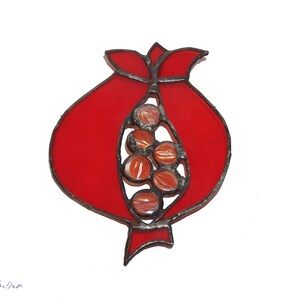 May include: A stained glass pomegranate with red glass and brown glass seeds. The pomegranate is open and the seeds are visible.