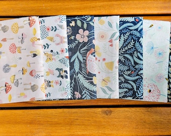May include: A set of eight fabric panels with different patterns. The panels feature a variety of designs, including mushrooms, flowers, leaves, and geometric shapes. The panels are all in shades of blue, green, white, and yellow.
