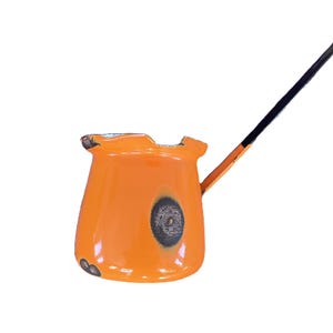 May include: Orange enamel coffee pot with a black handle. The pot has a round body and a spout. The handle is attached to the side of the pot.