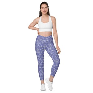 May include: Purple leggings with a white abstract face pattern. The leggings are cropped and have a high waist.